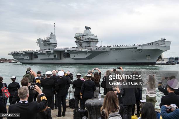 Members of the media and armed forces look on as HMS Queen Elizabeth sails into her home port of Portsmouth Naval Base on August 16, 2017 in...