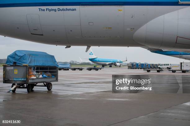 Mail sacks and packages sit in a trailer beneath an aircraft operated by KLM, the Dutch arm of Air France-KLM Group, at Schiphol airport in...