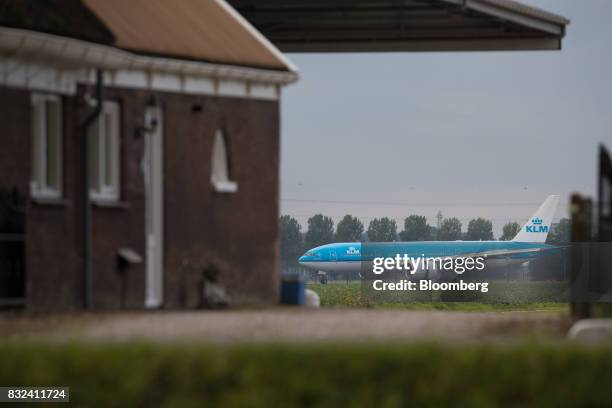 Passenger plane, operated by the Dutch arm of Air France-KLM Group, taxis beyond a farm building after landing at Schiphol airport in Amsterdam,...