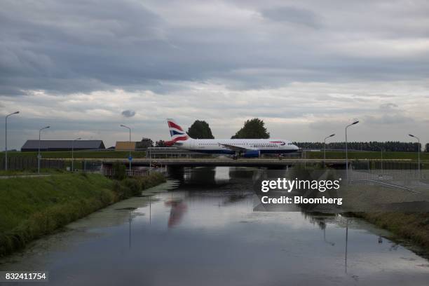 Passenger aircraft, operated by British Airways, a unit of International Consolidated Airlines Group SA , crosses a bridge after landing at Schiphol...