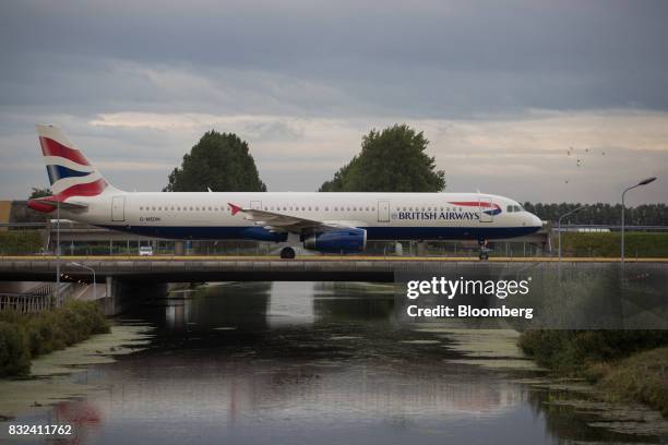Passenger aircraft operated by British Airways, a unit of International Consolidated Airlines Group SA , crosses a bridge after landing at Schiphol...