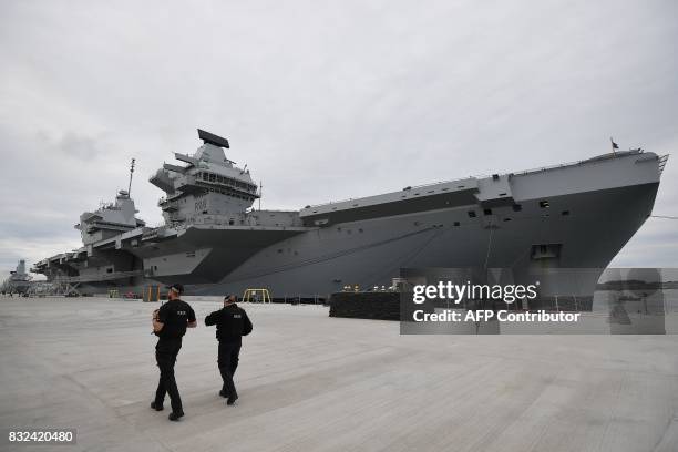 Armed police officers patrol the quayside next to the moored 65,000-tonne British aircraft carrier HMS Queen Elizabeth after it arrived at Portsmouth...