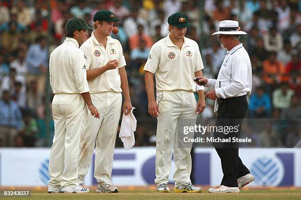 Umpire Rudi Koertzen of South Africa checks his light meter before bringing the players off field watched by Ricky Ponting , Cameron White and Shane...