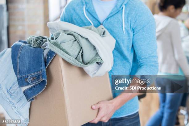 unrecognizable man donates clothing to shelter - clothing donation stock pictures, royalty-free photos & images