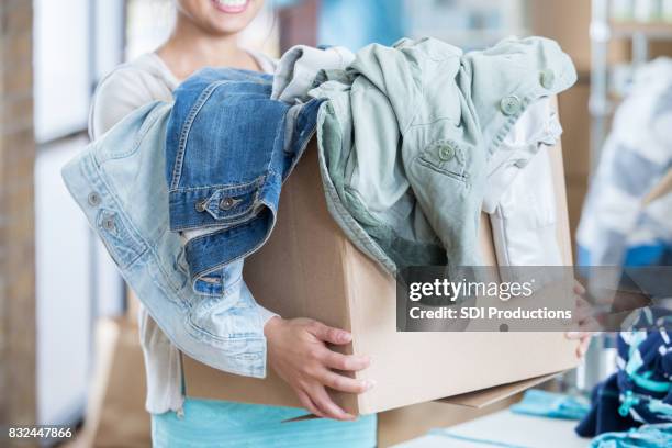 unrecognizable woman receives box of clothing during clothing drive - coat garment stock pictures, royalty-free photos & images