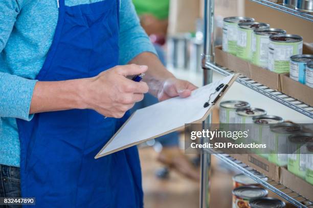 unrecognizable food bank volunteer works on inventory - expiry date stock pictures, royalty-free photos & images