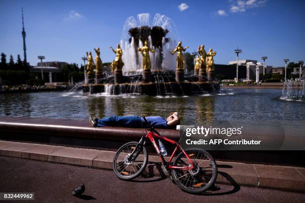 Cyclist rests on the famous Druzhba Narodov fountain in the All-Russia Exhibition Centre , a trade show and amusement park in Moscow on August 16,...