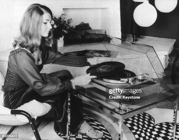 Woman using an automatic record player made by Philips, at the International Radio Show in Berlin, circa 1974. The turntable automatically places the...