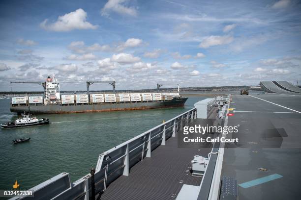 Container ship passes HMS Queen Elizabeth shortly after her arrival in Portsmouth Naval Docks on August 16, 2017 in Portsmouth, England. HMS Queen...