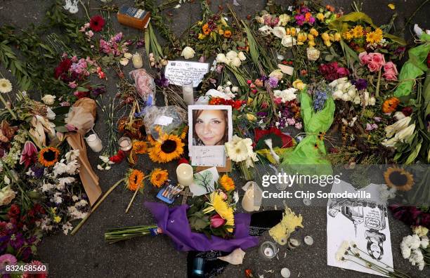 Flowers, candles and chalk-written messages surround a photograph of Heather Heyer on the spot where she was killed and 19 others injured when a car...