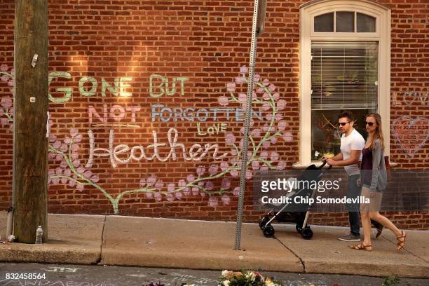 People walk past the informal memorial set up at the site where Heather Heyer was killed and 19 others injured when a car slamed into a crowd of...