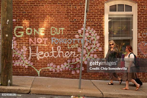 People walk past the informal memorial set up at the site where Heather Heyer was killed and 19 others injured when a car slamed into a crowd of...