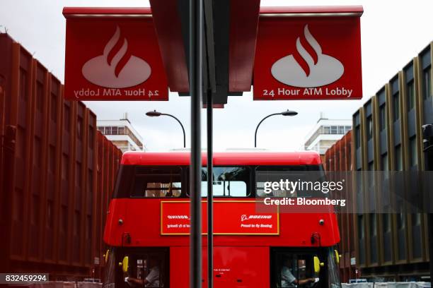 Bus passes signage for a bank branch of Banco Santander SA in London, U.K., on Tuesday, Aug. 15, 2017. Banco Santander, Spains biggest lender, has...
