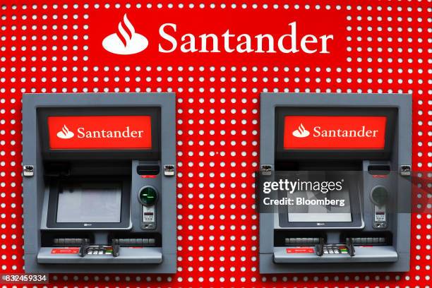 Automated teller machines stand outside a bank branch of Banco Santander SA in London, U.K., on Tuesday, Aug. 15, 2017. Banco Santander, Spains...