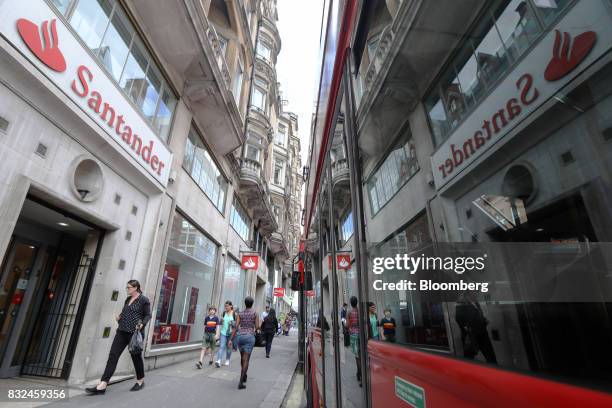 Window of a bus reflects signage of Banco Santander SA as it passes a bank branch in London, U.K., on Tuesday, Aug. 15, 2017. Banco Santander, Spains...