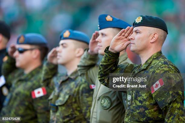 Members of the Canadian Forces salute during the national anthem before the game between the BC Lions and the Saskatchewan Roughriders at Mosaic...