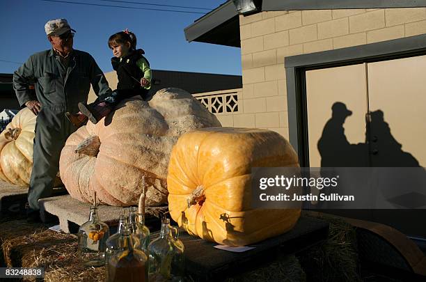 Pumpkin farmer John Mueller stands next to his oversized pumpkins with a young girl at the 35th Annual Safeway World Championship Pumpkin Weigh-Off...