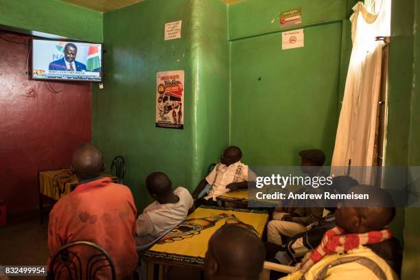 Men watch opposition candidate Raila Odinga speak at a press conference in a bar in the Mathare North neighborhood, on August 16, 2017 in Nairobi,...