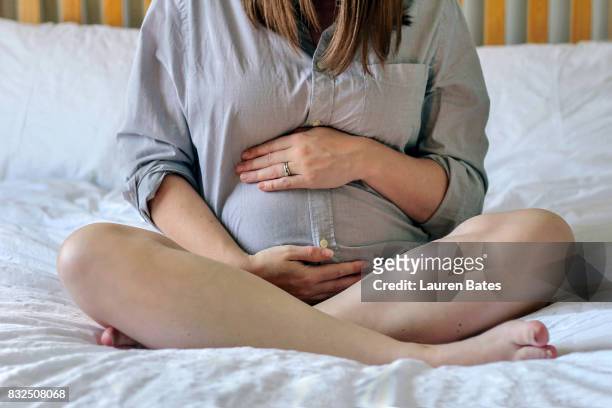 pregnant woman sitting on bed - maternity wear - fotografias e filmes do acervo