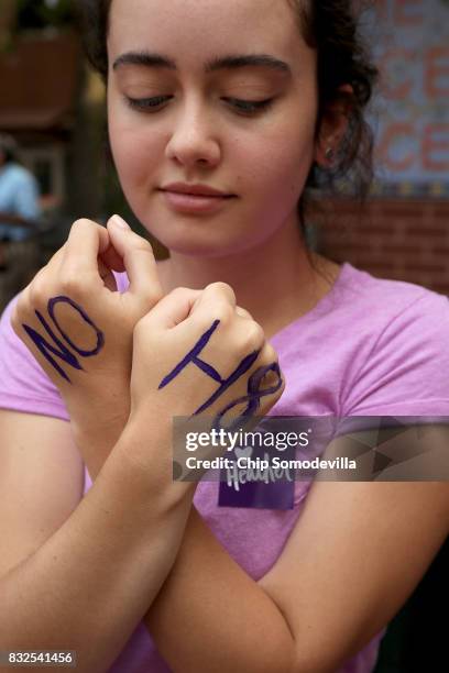 Mia Jones shows off the "NO H8" message written on her hands as she waits to attend the memorial service for Heather Heyer, who was killed when a car...