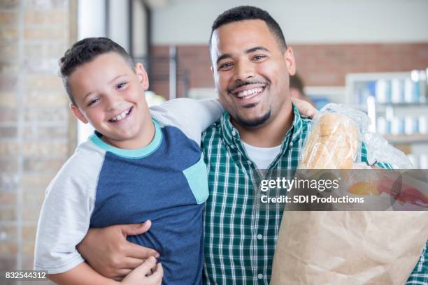 father and son receive bag of food during food drive - food bank stock pictures, royalty-free photos & images