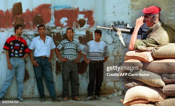 An Israeli paratrooper behind sandbags guards Palestinian youths detained after violating the curfew imposed on Palestinians, 04 October in the West...