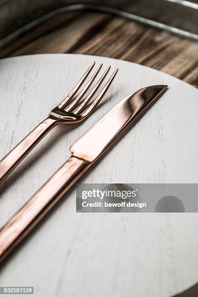 copper colored cutlery on white wooden board - besteck stock pictures, royalty-free photos & images