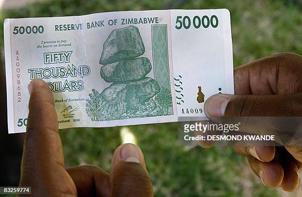 Zimbabwean holds the new 50 thousand dollar note released in Harare on October 14, 2008 as the country battles with inflation which is rapidly...