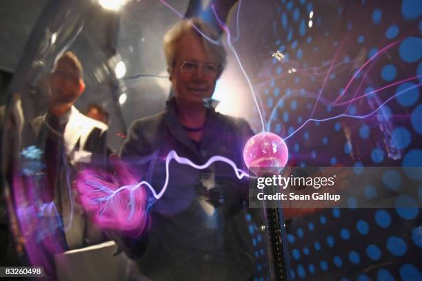 German Education Minister Annette Schavan watches as electrostatic energy glows under her hands in a glass sphere at the "Weltmaschine " exhibition...