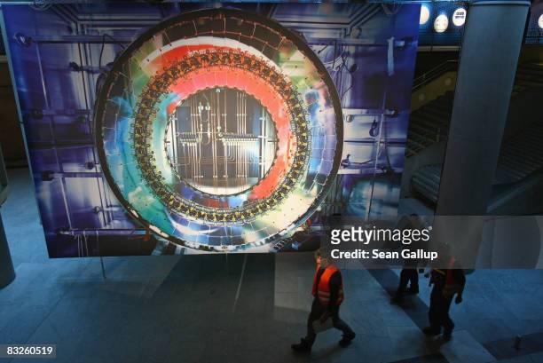 Workers walk past a giant photograph of a part of the Large Hadron Collider at the "Weltmaschine " exhibition on October 14, 2008 in Berlin, Germany....