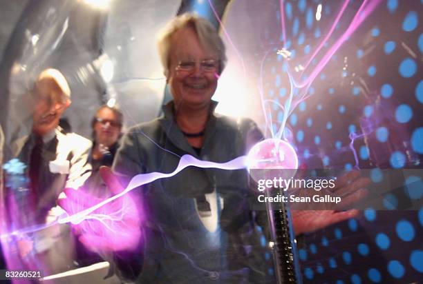 German Education Minister Annette Schavan smiles as electrostatic energy glows under her hands in a glass sphere at the "Weltmaschine " exhibition on...