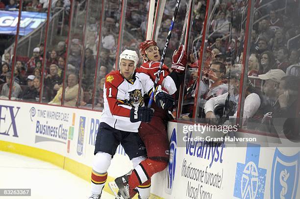 Joe Corvo of the Carolina Hurricane is checked by Gregory Campbell of the Florida Panthers on October 10, 2008 at the RBC Center in Raleigh, North...