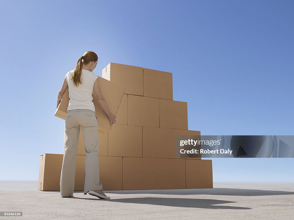 Woman stacking boxes in desert