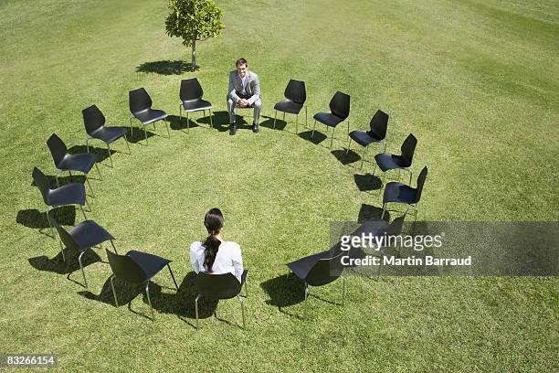business people sitting in circle of office chairs in field - businessman challenge stock pictures, royalty-free photos & images
