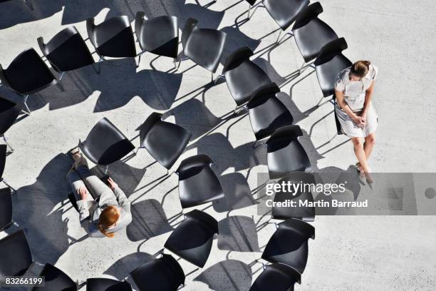 businesswomen sitting in spiral of office chairs - continuity stockfoto's en -beelden