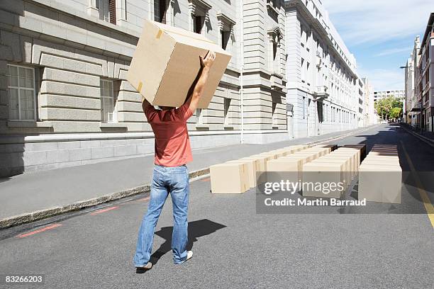 man carrying box in roadway - carrying box stock pictures, royalty-free photos & images