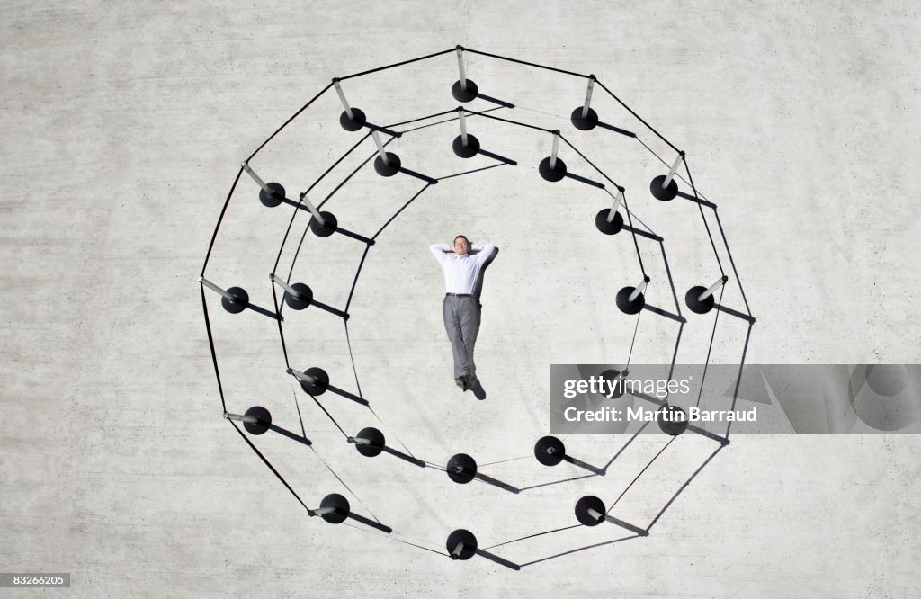 Businessman laying in circle of cordon posts