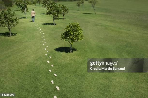 man walking leaving trail of footprints - green footprint stock pictures, royalty-free photos & images