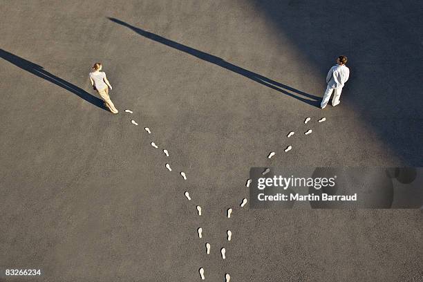 man and woman with diverging line of footprints - in a row stockfoto's en -beelden