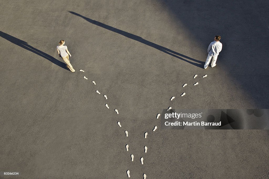 Man and woman with diverging line of footprints
