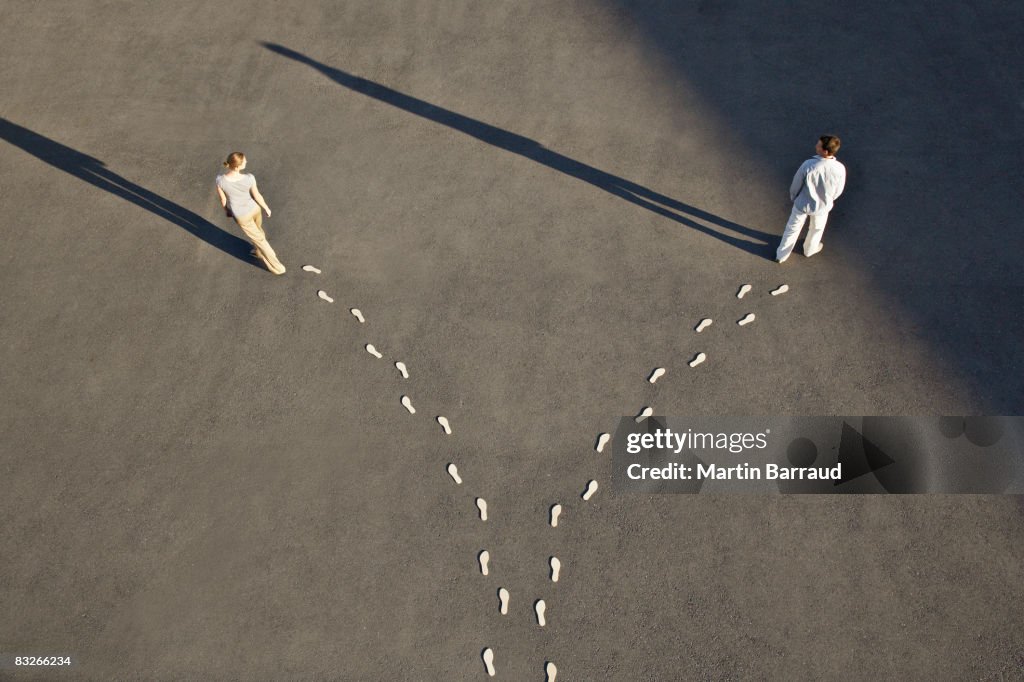 Man and woman with diverging line of footprints