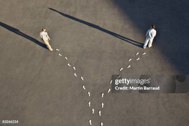 man and woman with diverging line of footprints - alternativ bildbanksfoton och bilder