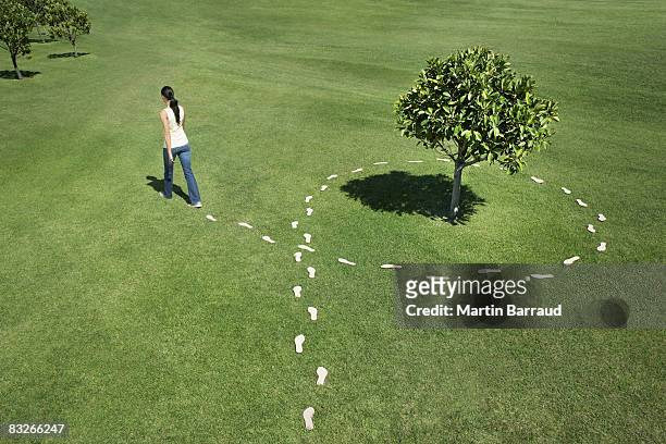 woman walking leaving trail of footprints - green footprint stock pictures, royalty-free photos & images