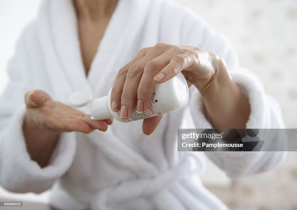 Mature woman applying moisturizer