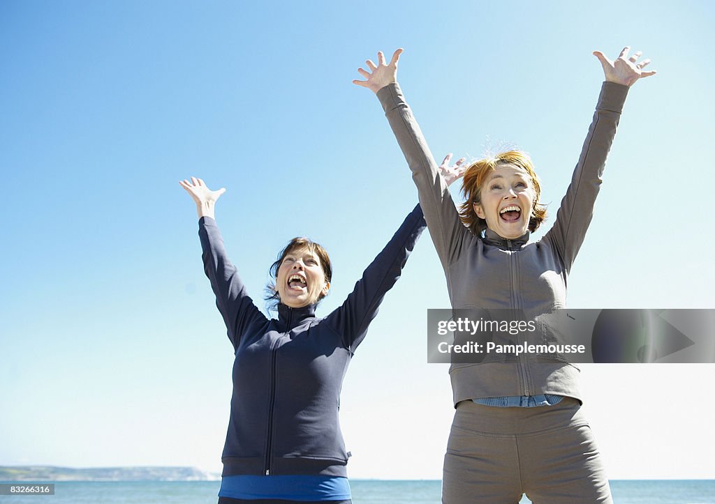 Two mature women cheering on beach