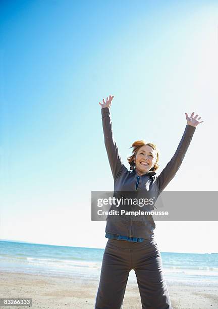 mature woman stretching on beach - une seule femme d'âge mûr photos et images de collection