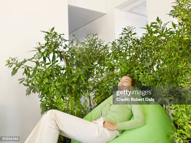 businesswoman on beanbag surrounded by plants - room plant stock pictures, royalty-free photos & images