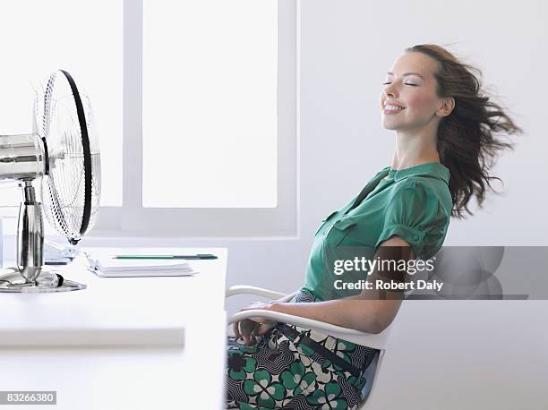 mujer de negocios en oficina con ventilador - refrescante fotografías e imágenes de stock