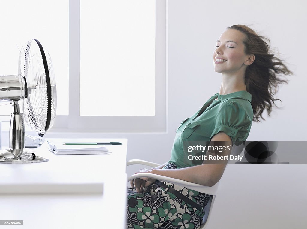 Businesswoman enjoying fan in office