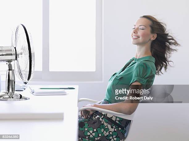 businesswoman enjoying fan in office - electric fan stock pictures, royalty-free photos & images